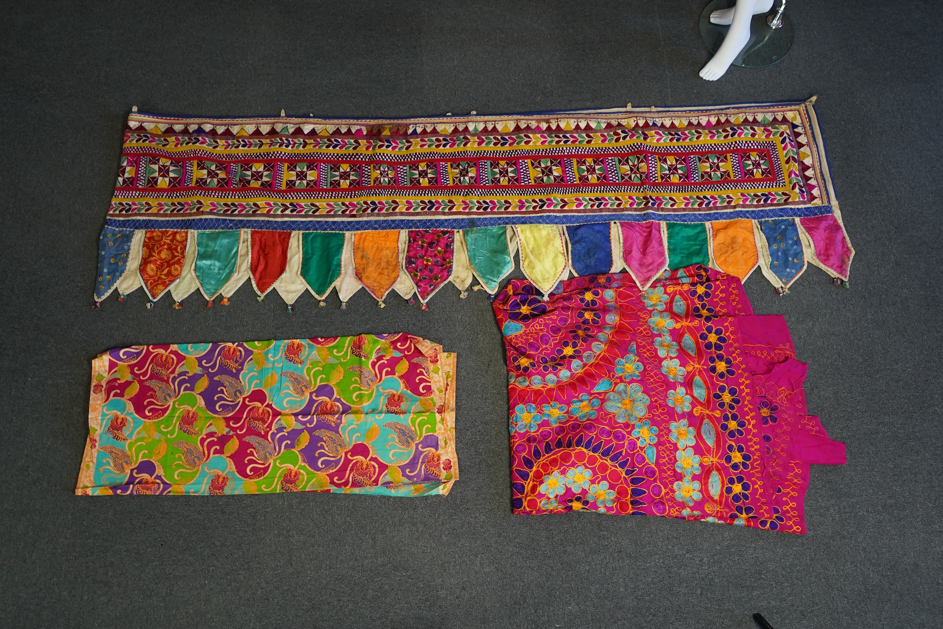 A large Indian silk embroidered and mirrored temple pelmet, with a cerise silk embroidered hanging and a length of cotton wax resist style printed fabric. Temple pelmet 468cm long x 70cm, deep. Condition - the pelmet has